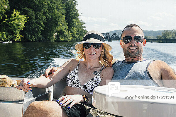 Couple relaxing with arms around each other in boat on sunny day