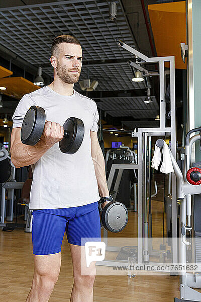 Young man lifting dumbbells at gym