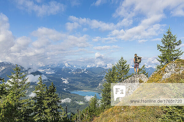 Male hiker admiring view of Sylvenstein Reservoir and surrounding mountains