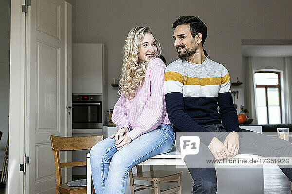 Boyfriend and girlfriend sitting on table at home