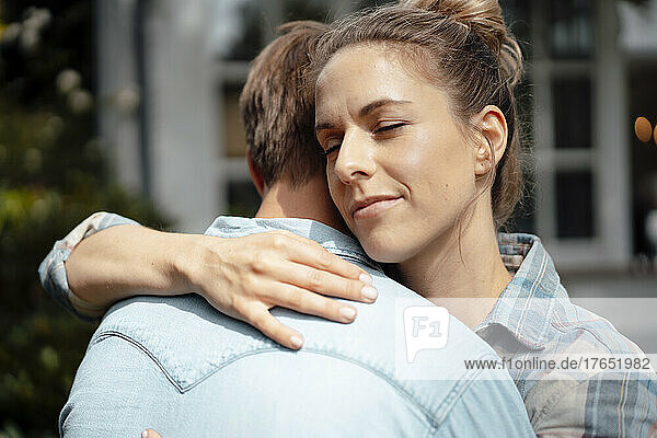 Blond woman with eyes closed hugging boyfriend