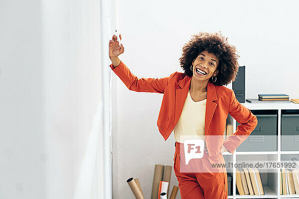 Cheerful businesswoman standing with hand on hip in office