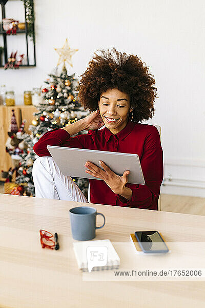 Smiling woman with tablet PC sitting in living room at home