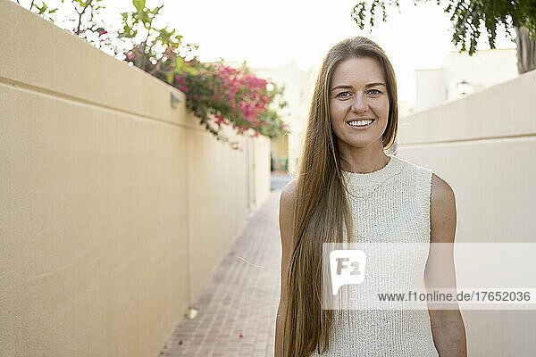 Smiling woman with long blond hair on footpath