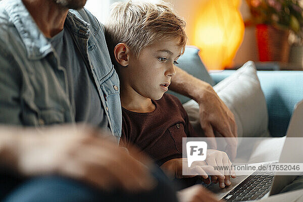 Boy using laptop sitting by parents at home