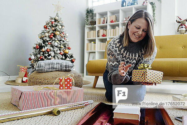 Glückliche Frau  die zu Hause Geschenke mit Geschenkpapier verpackt