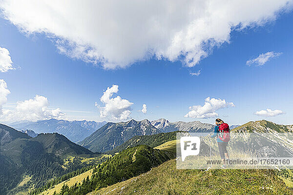Woman with hiking pole standing on mountain