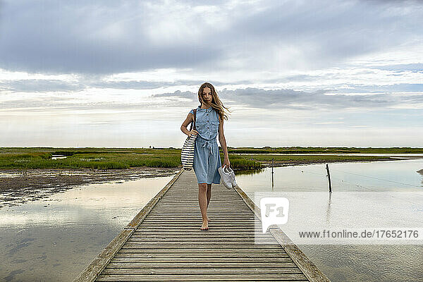 Girl with tousled hair walking barefoot on jetty