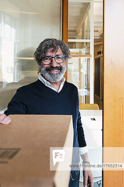 Smiling senior man receiving package at home