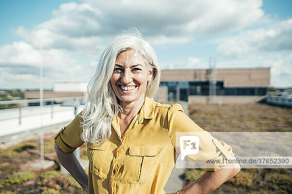 Glückliche Geschäftsfrau mit grauen Haaren im Büropark an einem sonnigen Tag