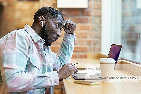 Freelancer using laptop sitting at cafe