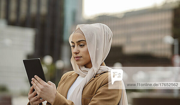 Young businesswoman wearing hijab using tablet PC