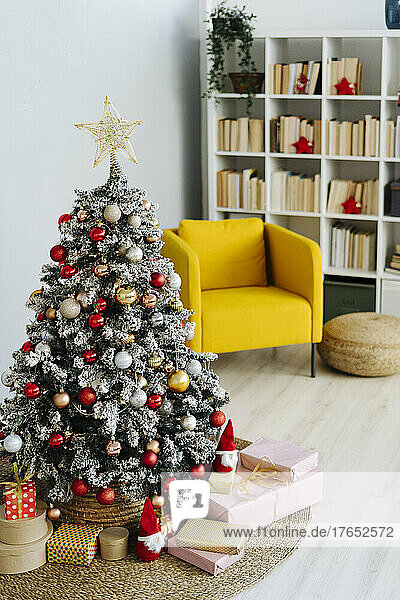 Decorated Christmas tree amidst gifts in living room at home