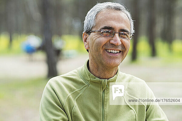 Happy mature man wearing eyeglasses in forest