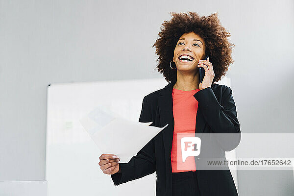 Happy businesswoman talking on mobile phone in office