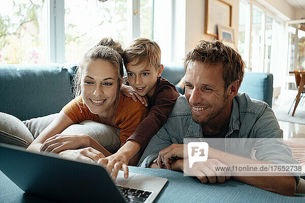 Happy mother and father with son watching video on laptop at home