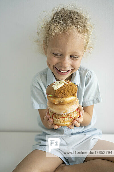 Lächelndes Mädchen hält einen Stapel Donuts auf dem Tisch