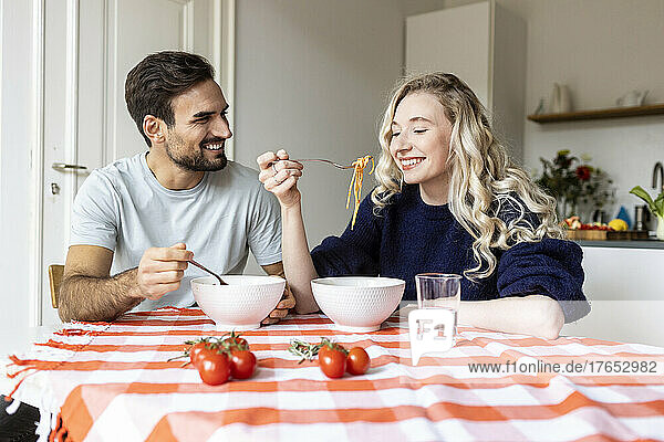 Couple eating food together on dining table at home