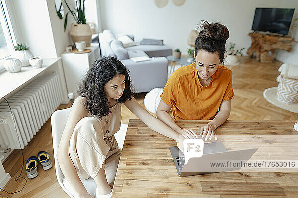 Teenage girl using laptop with mother at home