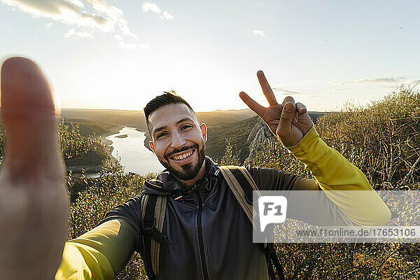 Männlicher Wanderer macht eine Friedensgeste  während er ein Selfie im Monfrague-Nationalpark macht