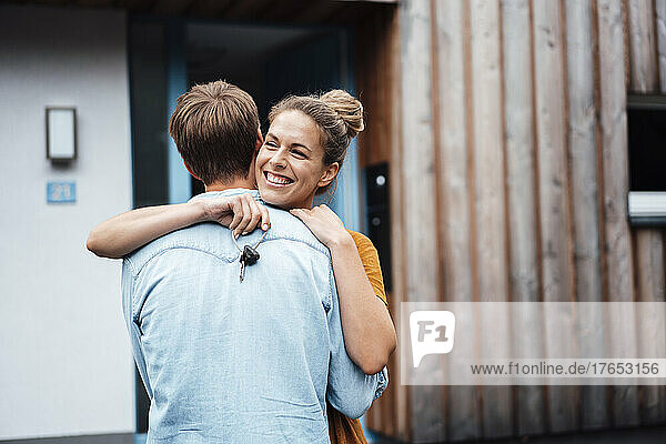 Happy woman with house key hugging boyfriend