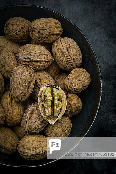 Studio shot of bowl of walnuts lying against black background