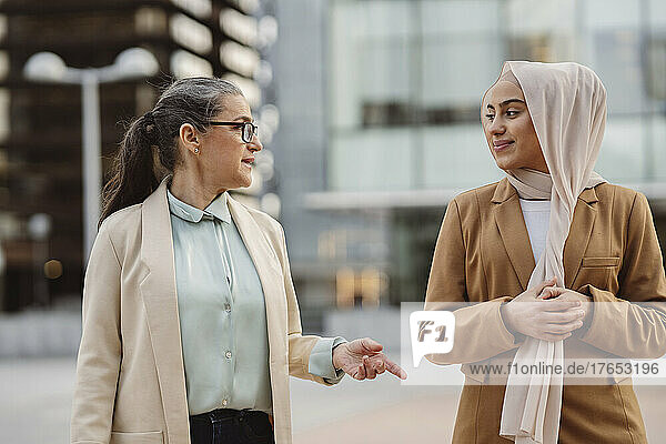 Businesswoman wearing eyeglasses talking with young colleague