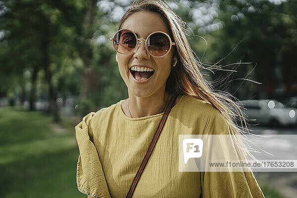 Happy blond woman wearing sunglasses in park
