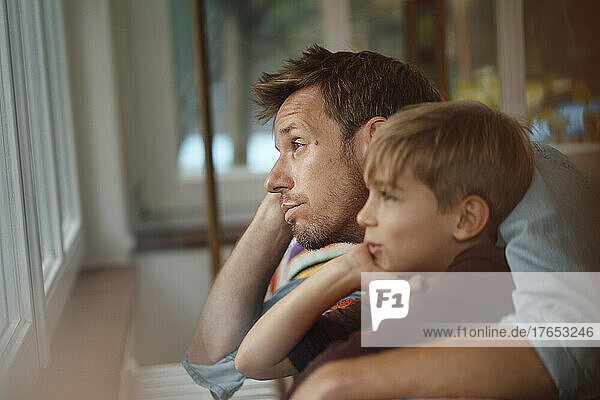 Bored man sitting with son at home
