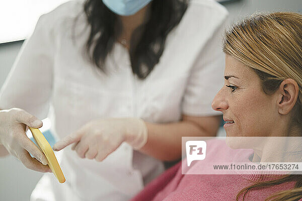 Zahnarzt erklärt Patient per Mobiltelefon in der Zahnklinik
