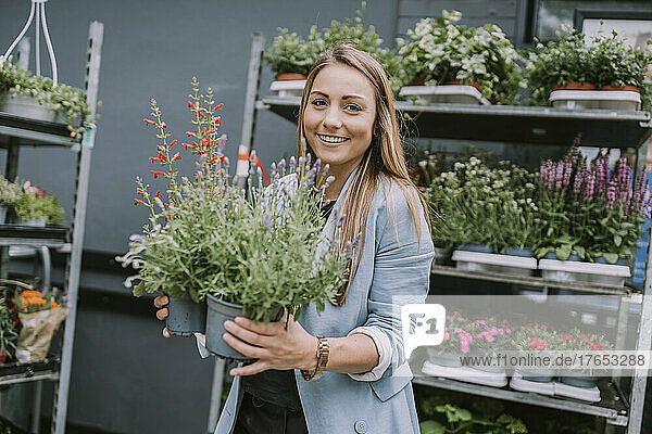 Happy young woman buying plants at garden center