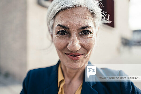 Smiling businesswoman with gray hair outside office building