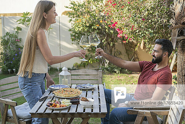 Couple toasting with wineglasses enjoying breakfast in garden