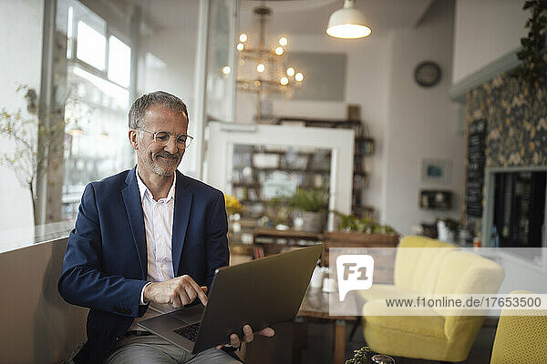 Smiling businessman using laptop in cafe