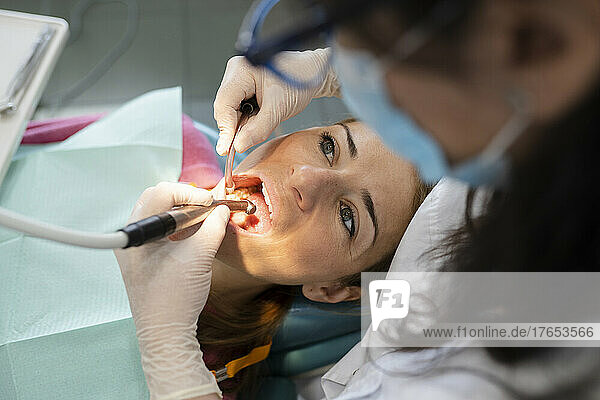 Dentist examining patient teeth with dental equipment at medical clinic