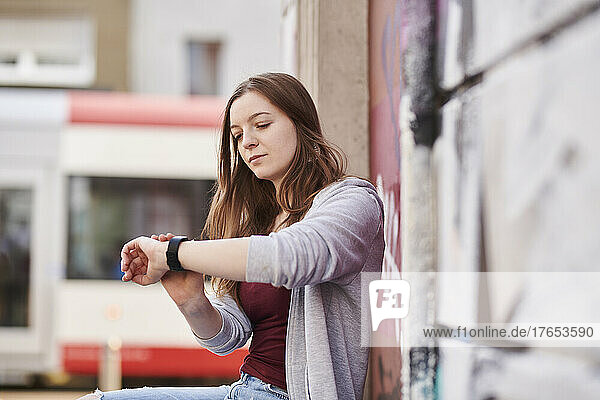 Young woman checking the time sitting in the city