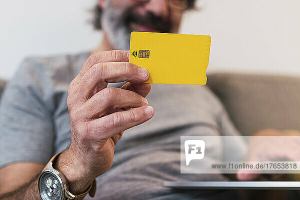 Mann benutzt Kreditkarte  um zu Hause Finanzrechnungen zu bezahlen