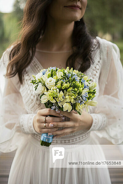 Smiling bride holding flower bouquet