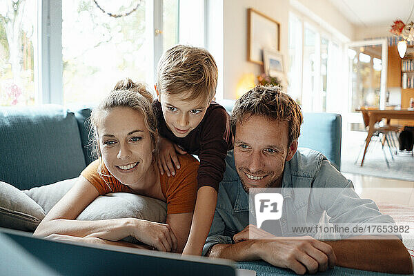 Glückliche Eltern mit ihrem Sohn  die zu Hause Videos auf dem Laptop ansehen