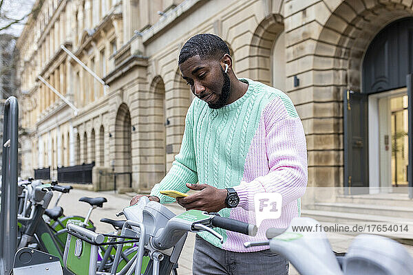 Mann scannt per Smartphone und mietet Fahrrad am Parkplatz
