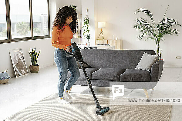 Young woman with vacuum cleaner doing housework at home