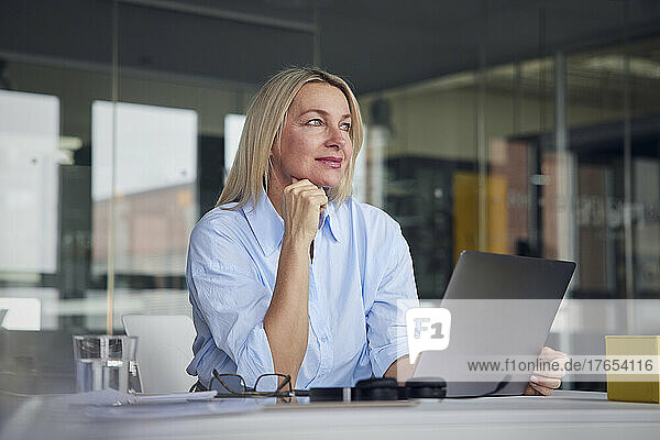 Businesswoman with hand on chin at desk in office