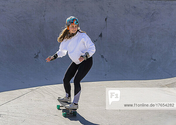 Young woman practicing skateboarding on pump track