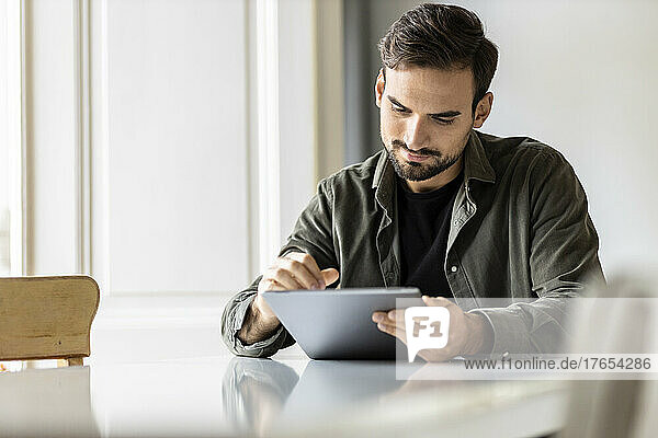 Man sitting at table using tablet PC at home
