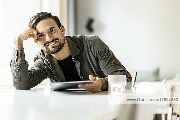 Man with tablet PC leaning on table at home