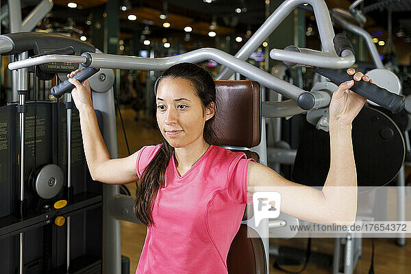 Young woman doing workout with exercise machine in gym