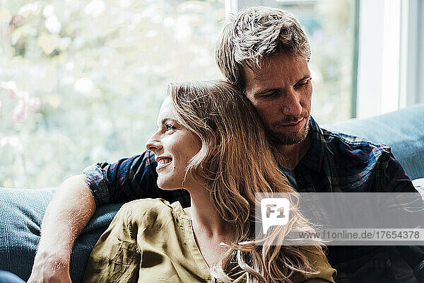 Smiling blond woman with boyfriend sitting on sofa at home