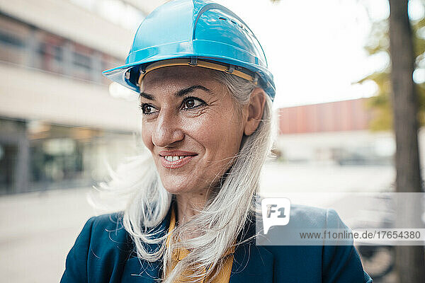 Smiling engineer wearing hardhat at office park