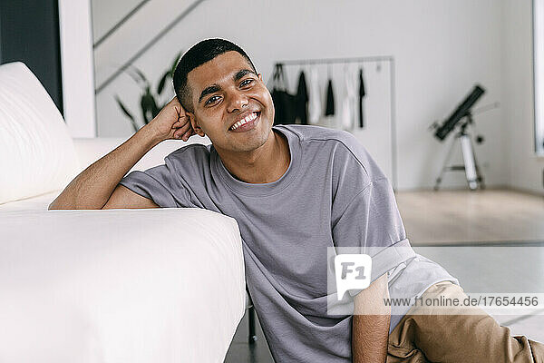Happy young man leaning on sofa sitting in living room
