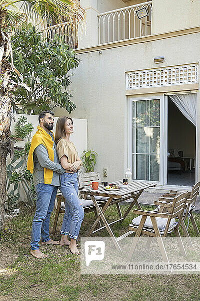 Happy couple standing by table in back yard garden